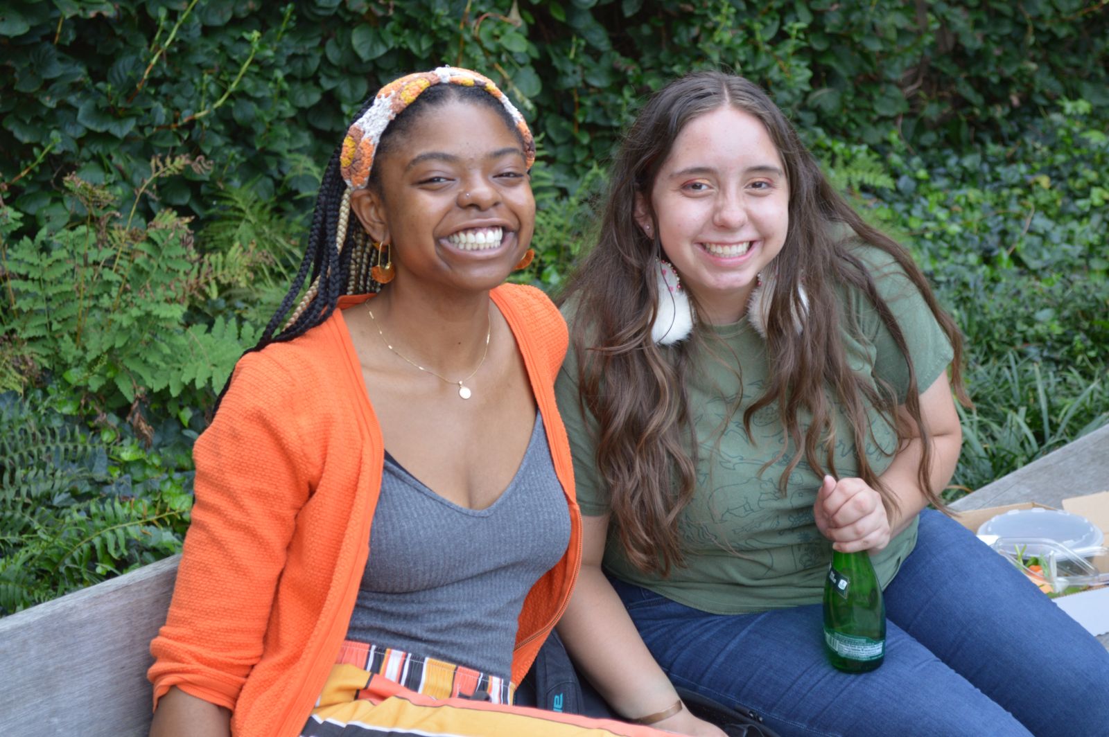 2 students sitting on a bench for the camera