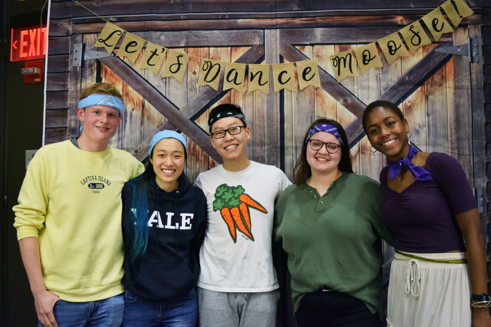 5 Yale friends taking a photo in front of a shed with the banner "Let's Dance Moose!"