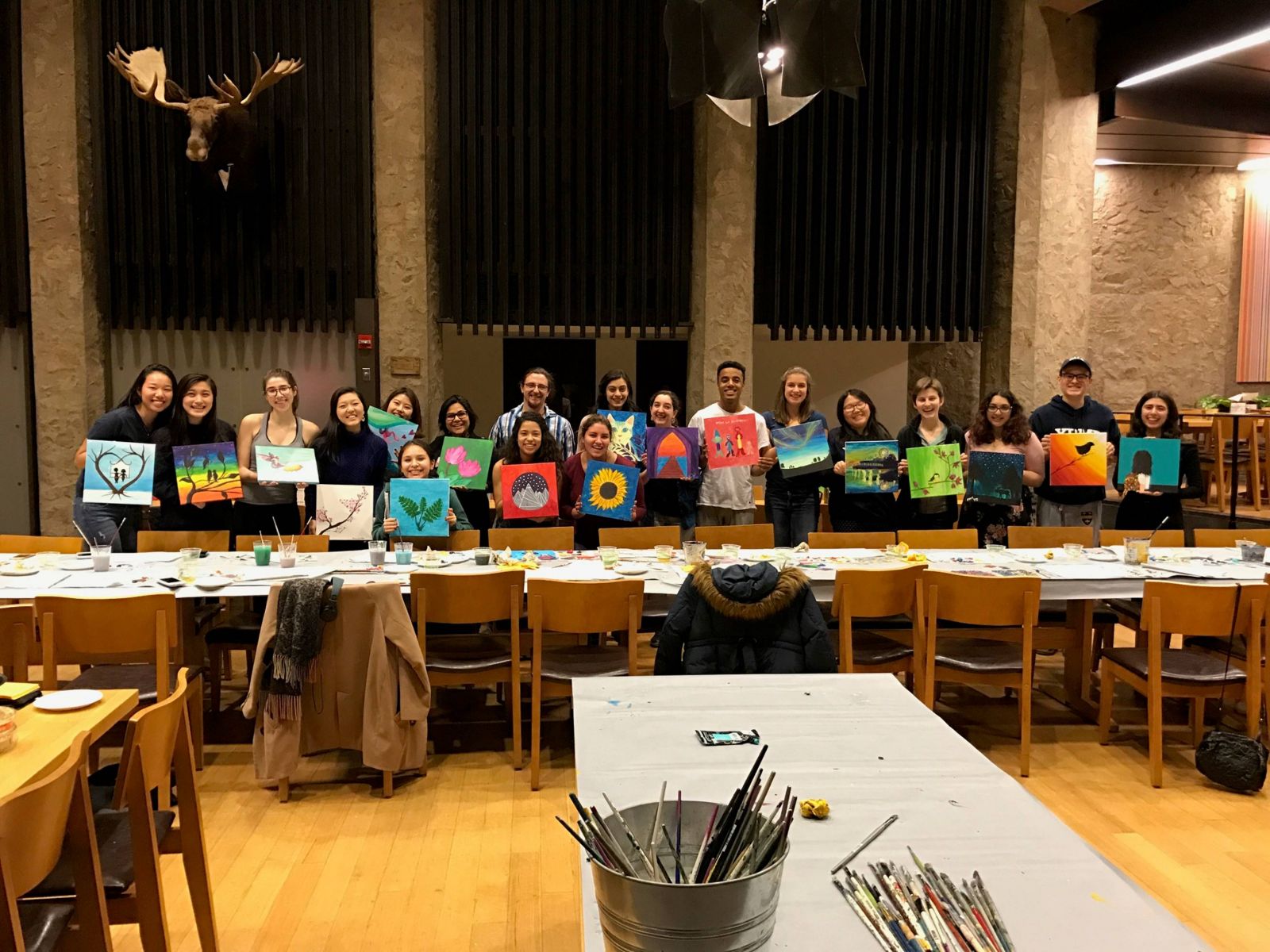 Students show off their paintings in a group photo
