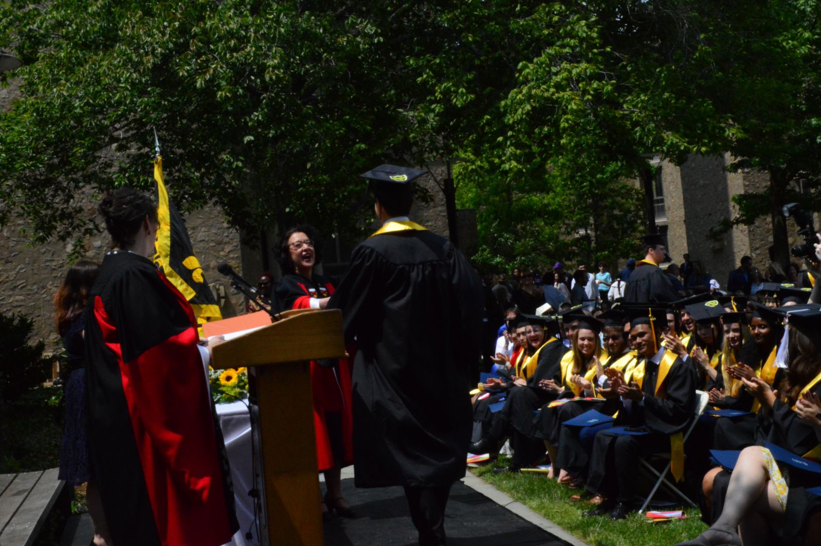 Graduating student walks to head of college on stage during commencement