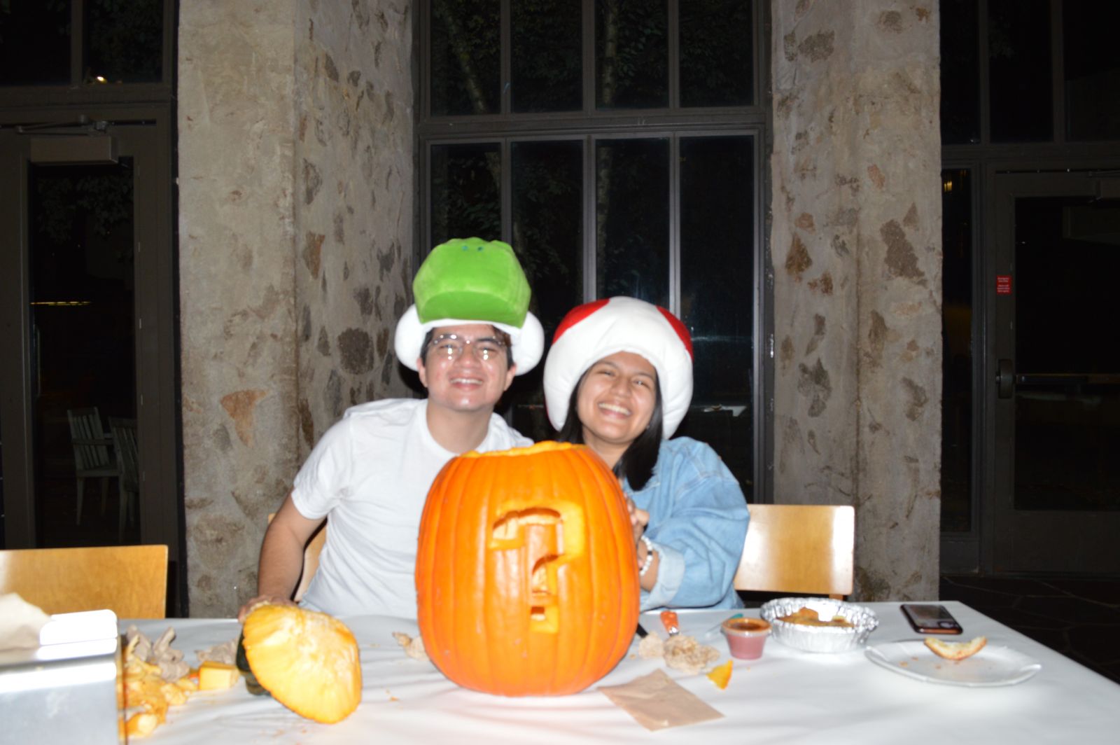 2 Stilesians taking picture with a pumpkin that has a question mark carved on it