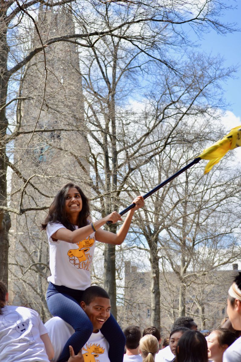 A student raises and waves the Ezra Stiles college flag