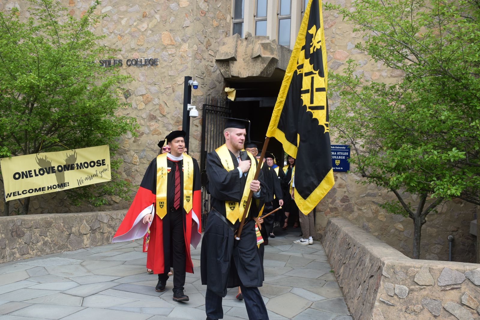 Banner Bearer walks in with the college flag in commencement
