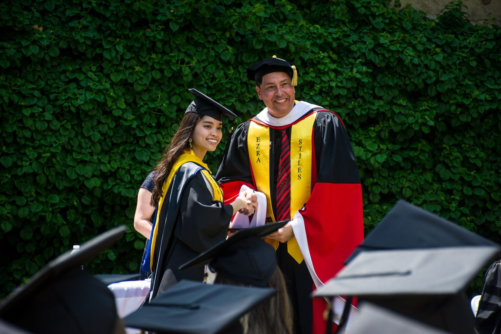 A yale student shaking hands with Head Pitti as she picks up her diploma