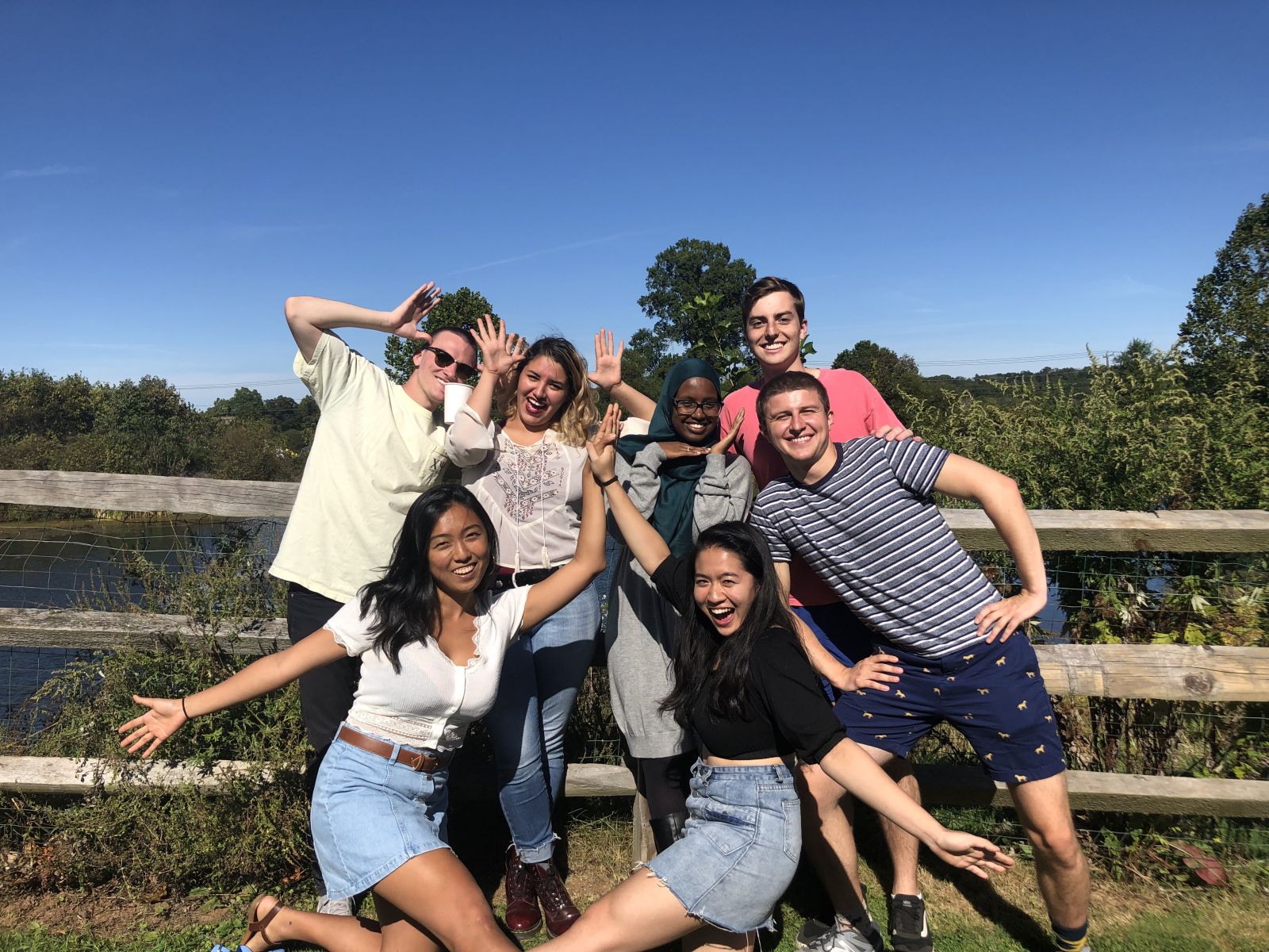A group of 7 friends having fun near the pond at the orchard