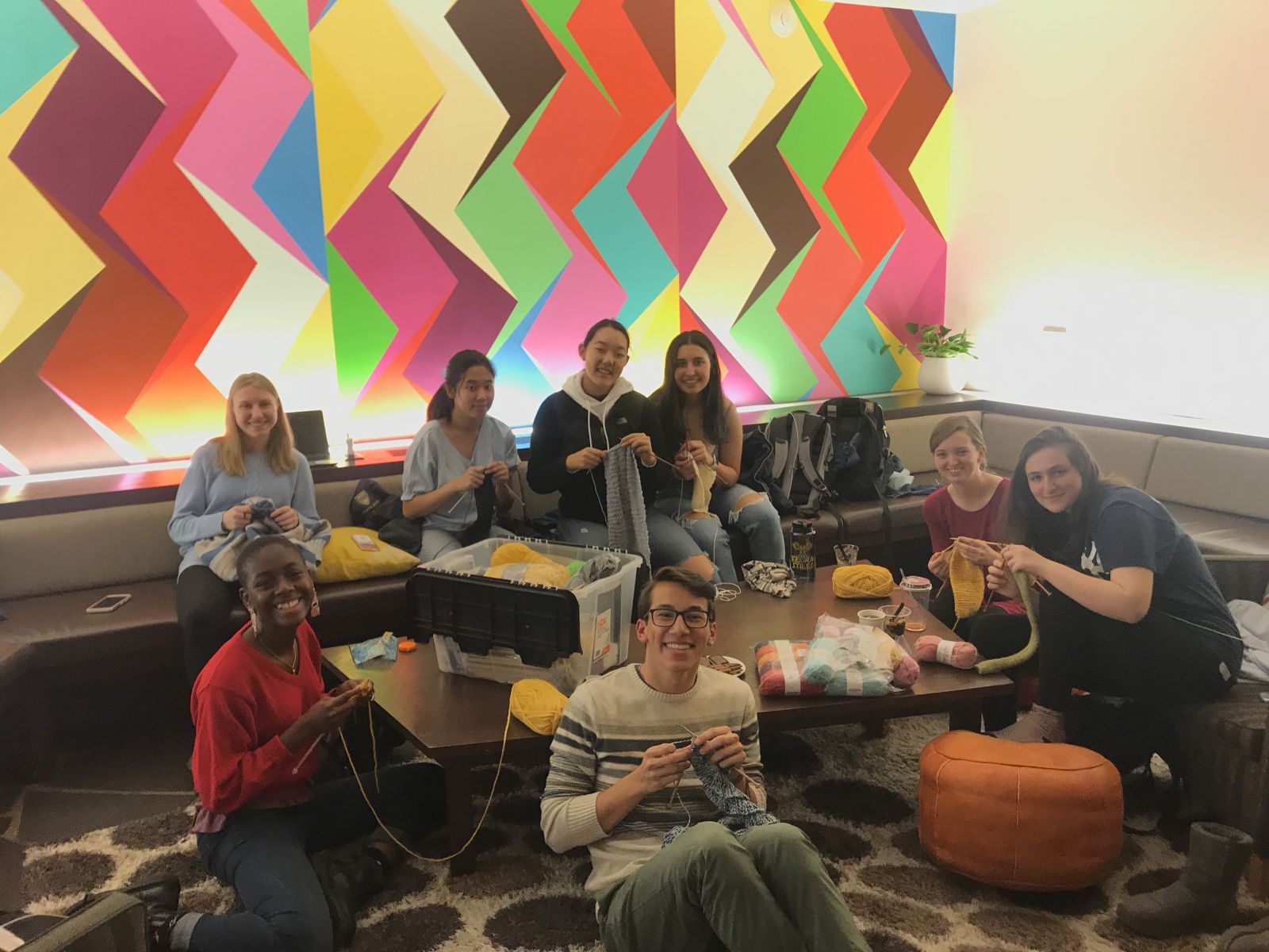 Group of students smiling while knitting for the photo