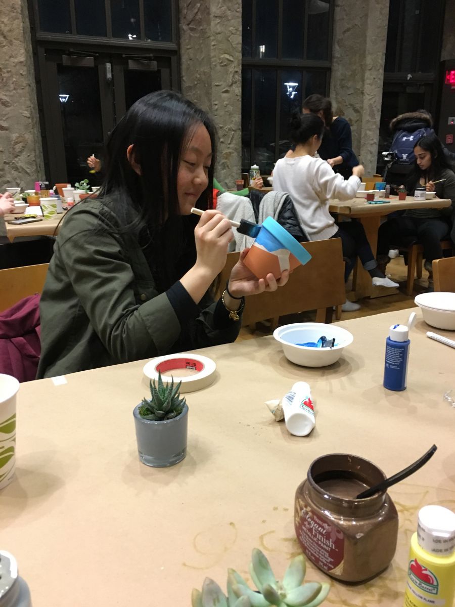 A student paints their flower pot at the houseplant party