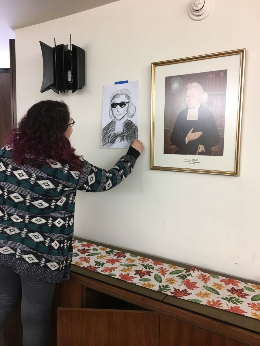 A student compares their picture of Ezra Stiles with shaded glasses to a portrait
