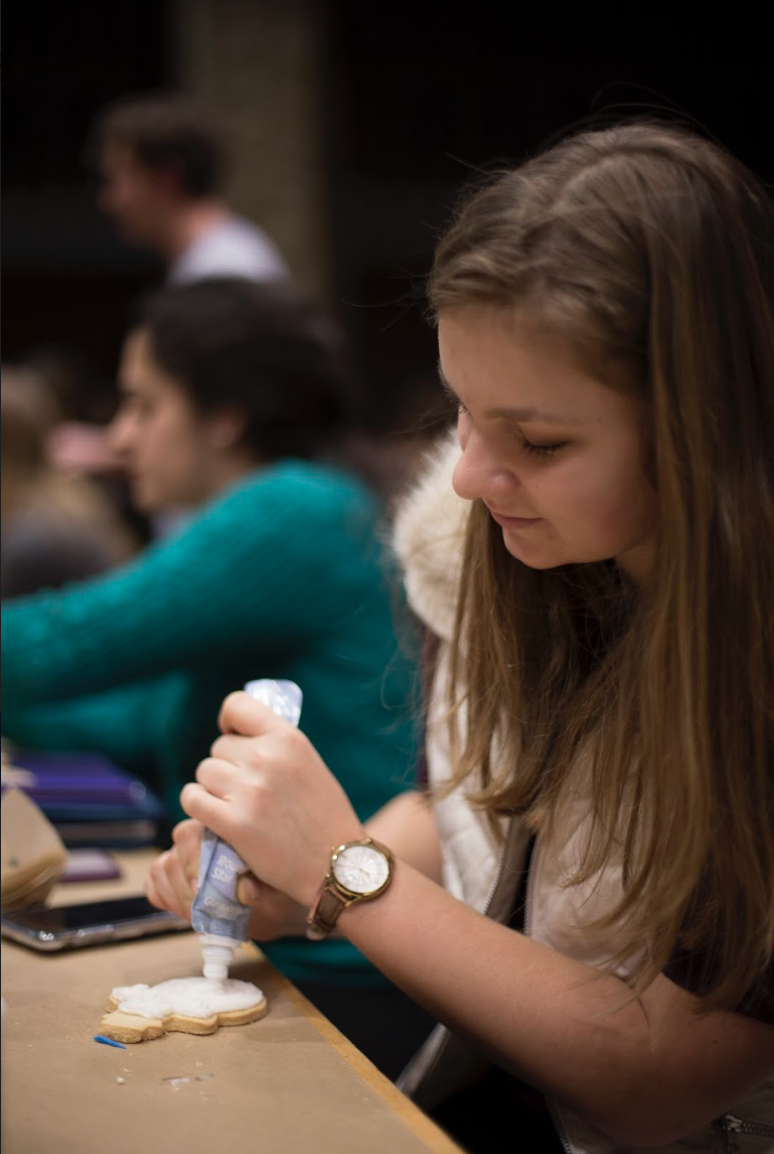 A student puts frosting on their cookie