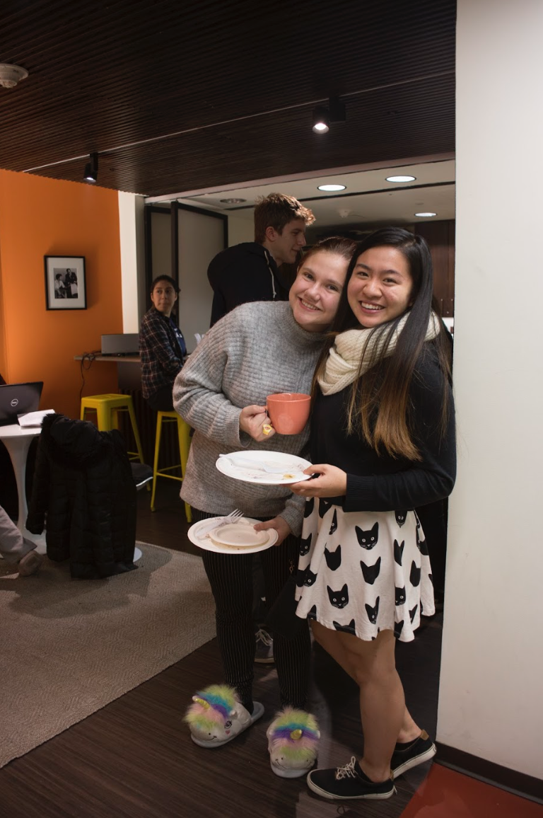 2 students holding plates with pancakes and a mug