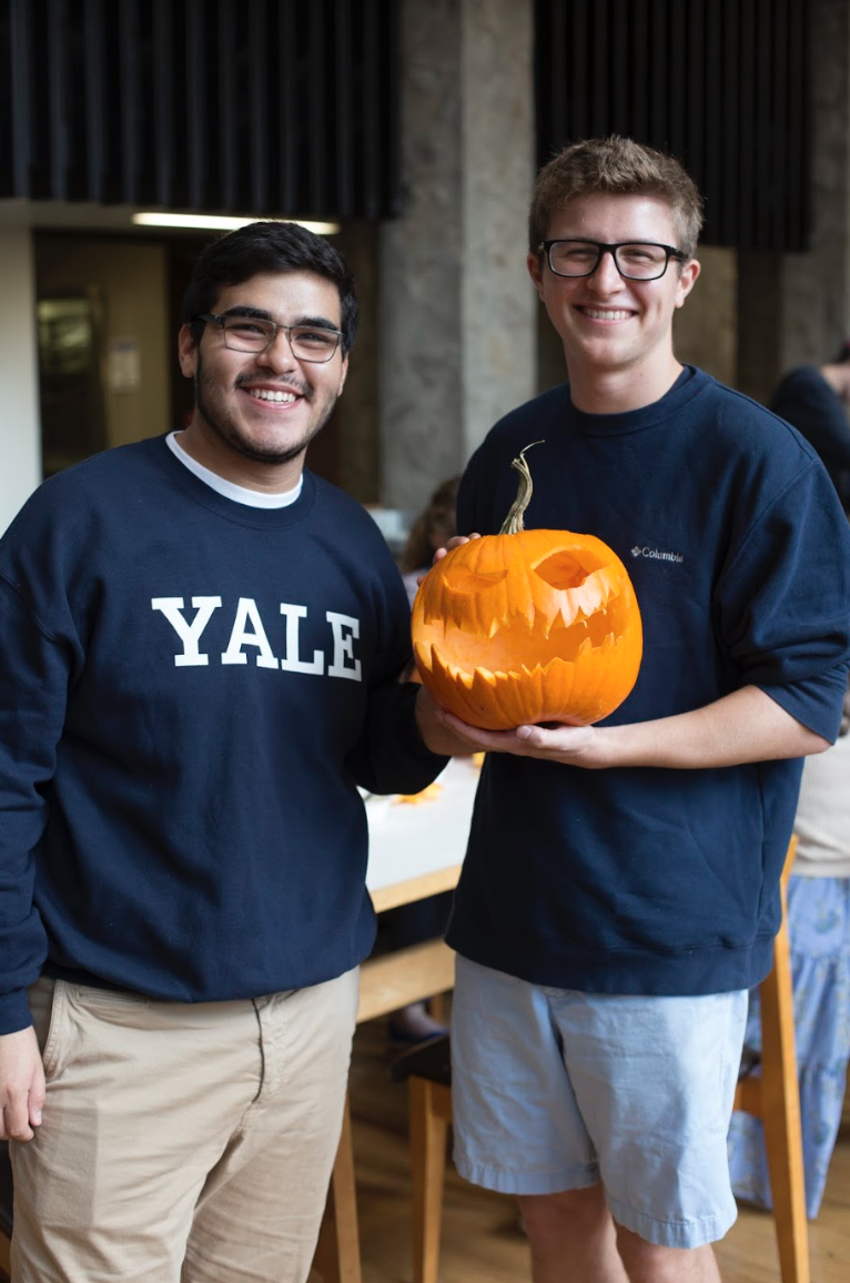 2 students show off their carved pumpkin with a scary face