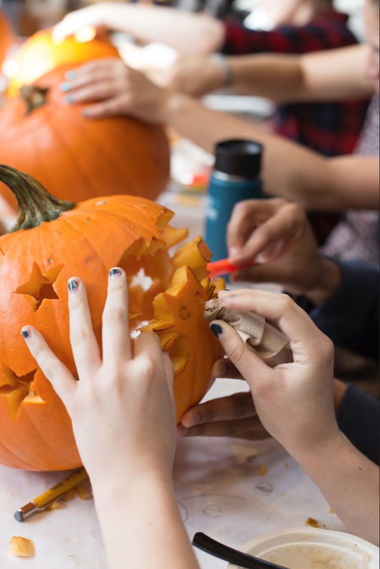 A student carving stars on their pumpkin