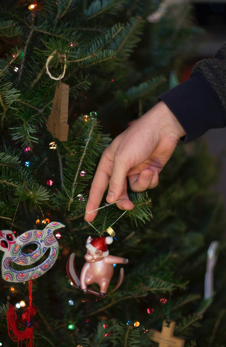 A student hangs up a pig ornament with a Santa Claus hat