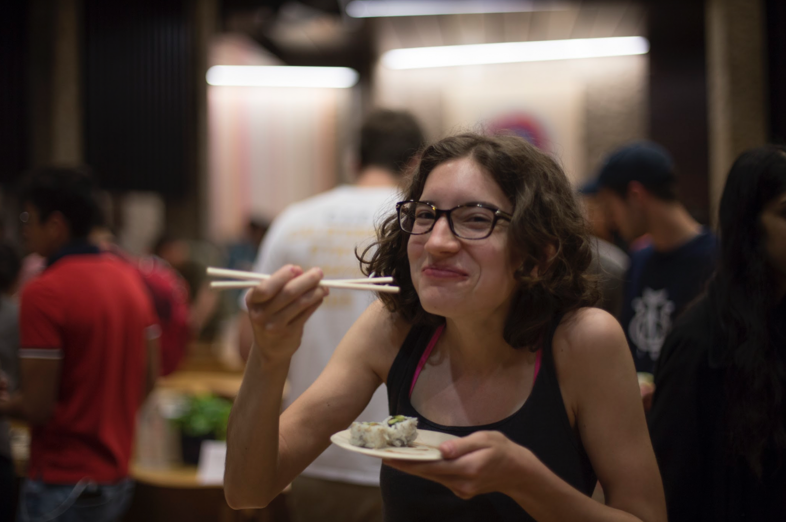 A student holding chopsticks enjoying their sushi 