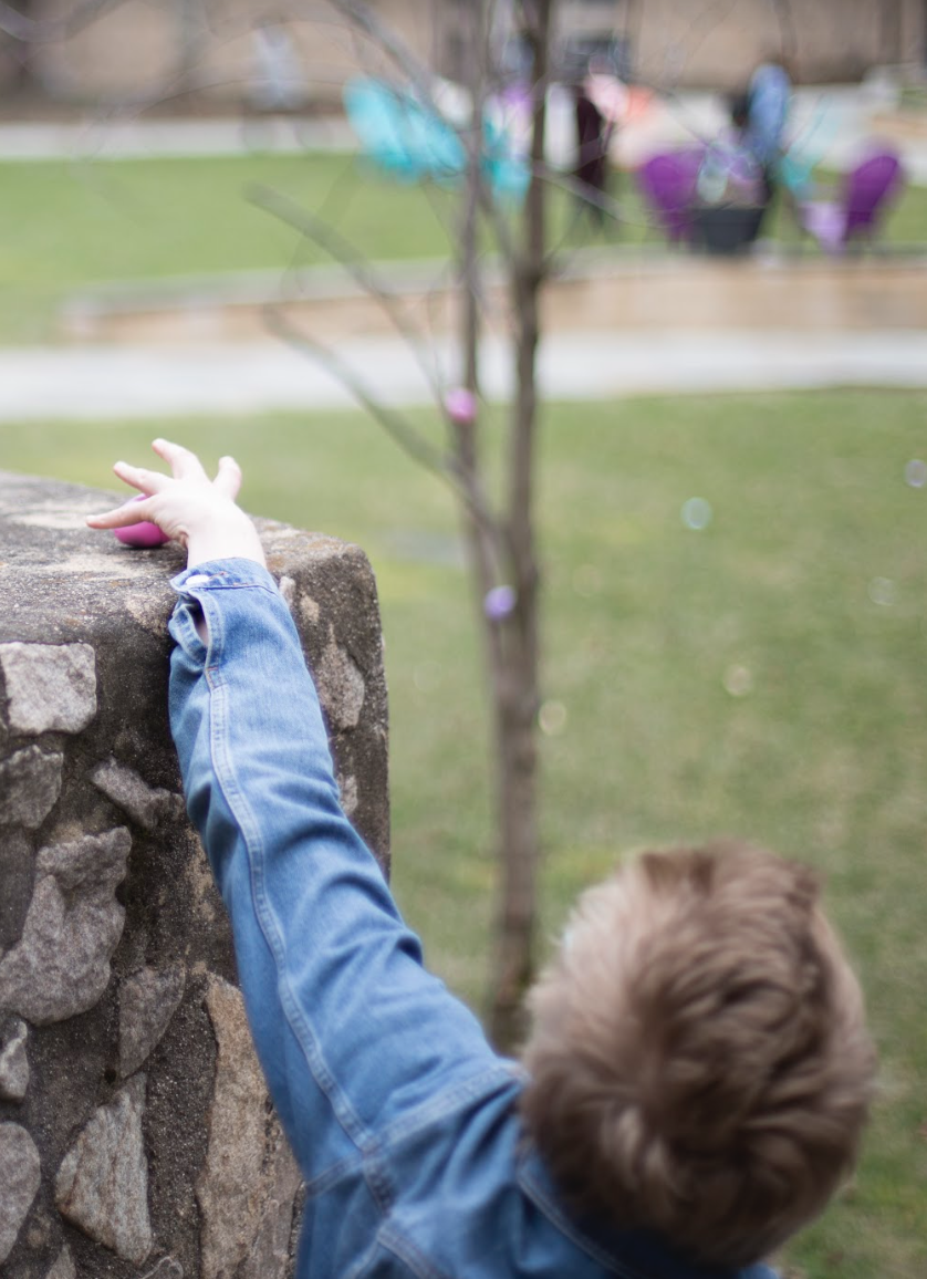 A little kid finds a pink egg at the courtyard