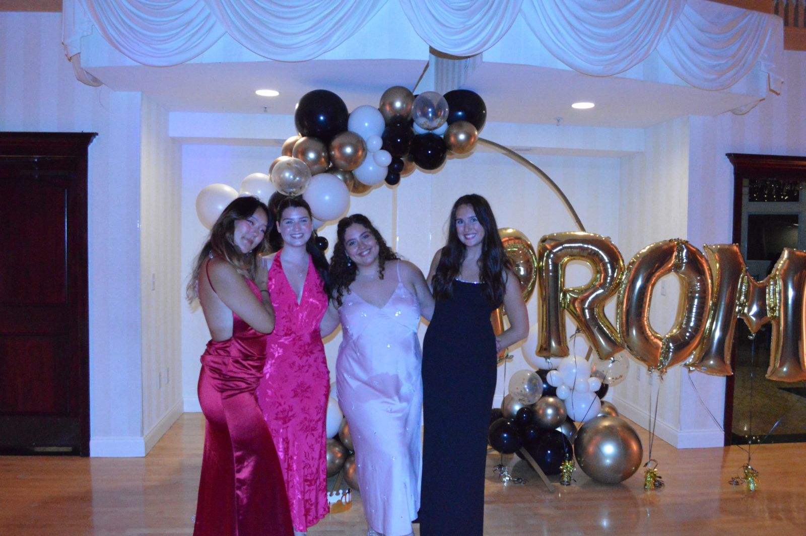 Friends taking group photo in front of prom balloons