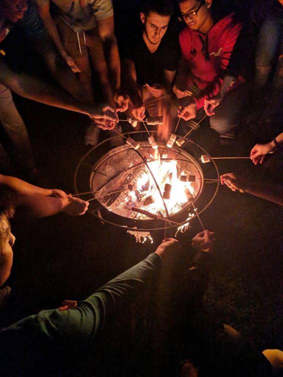 Mant students roasting their marshmellows above the fire