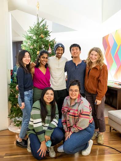 Group of friends at Ezra Stile standing in front of a christmas tree in their apartment
