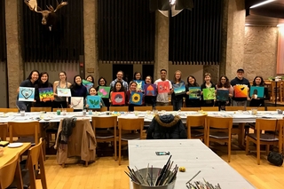 Students show off their paintings in a group photo