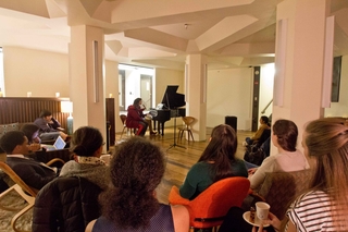 A lady plays on the piano for the open mic coffeehouse