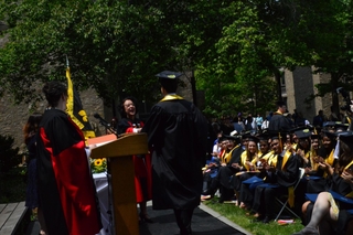 Graduating student walks to head of college on stage during commencement