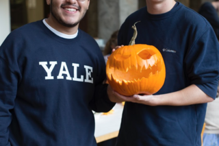 2 students show off their carved pumpkin with a scary face
