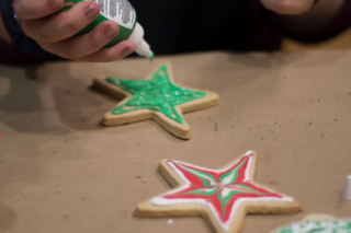 A student made 3 star cookies and is putting green frosting on one