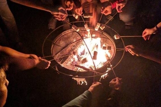 Mant students roasting their marshmellows above the fire