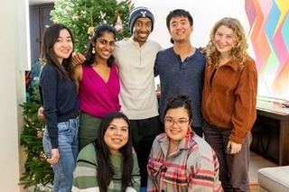 Group of friends at Ezra Stile standing in front of a christmas tree in their apartment